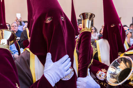 Linares, Jaen province, SPAIN - March 17, 2014  Nazarenes with red tunics and trumpets in the hands...