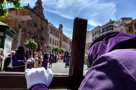 Penitent praying on his cross in front of church during Holy week procession, Spainの写真素材