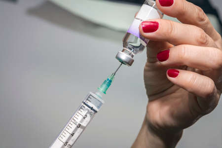 Women with nails painted with red sucks medication with syringe