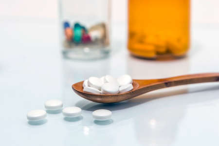 Wooden spoon with pills white on white backgroundの写真素材