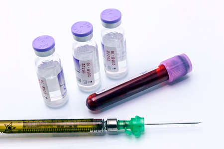 Syringe and blood test tube on white background