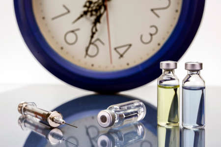 medicine vials and syringe, the clock shows the time of the medication