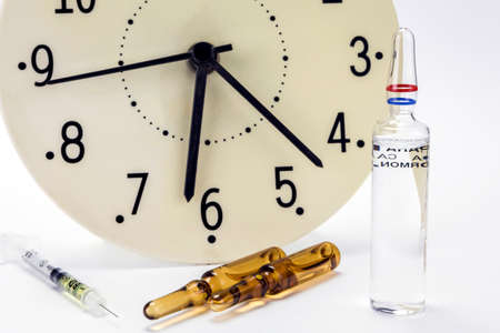 medicine vials and syringe, the clock shows the time of the medicationの写真素材