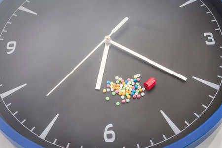 Open red capsule pill with ball color drug on black clock backgroundの写真素材