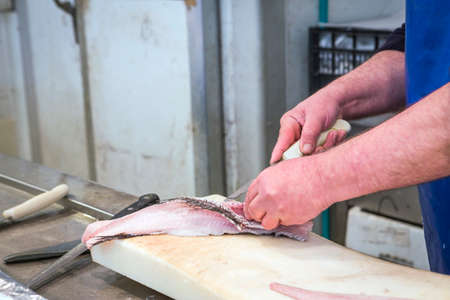 Fish seller short with a thin knife on the market of Cadiz, Andalusia, Spainの写真素材