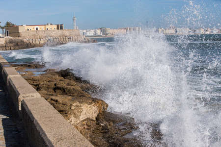Waves hit the rocks on the promenade of the La Caleta beach in Cadiz, Spainの写真素材