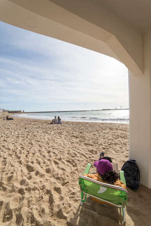 Cadiz Spain- April 1: Caleta beach in the middle of the old city is the most popular of the beaches, Group of young people enjoying a sunny afternoon sitting in the sand, take in Cadiz, Andalusia, Spainのeditorial素材