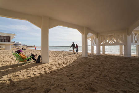 Cadiz Spain- April 1: Caleta beach in the middle of the old city is the most popular of the beaches, Group of young people enjoying a sunny afternoon sitting in the sand, take in Cadiz, Andalusia, Spainのeditorial素材