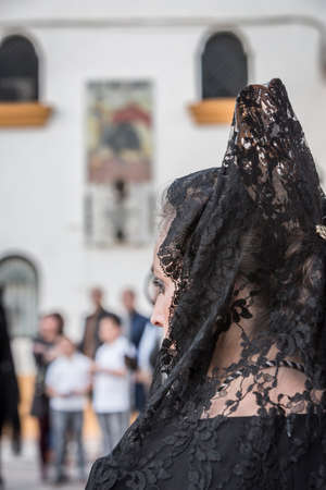 Linares, SPAIN - April 12: Women dressed in typical suit of Spanish mantilla, to fund the bullring of Linares and poster of the anniversary of the death of Manolete during Holy Week, Linares, Andalucia, Spainのeditorial素材