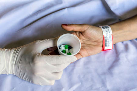 Nurse delivers dose of daily medication and pills a woman admitted to hospitalの写真素材