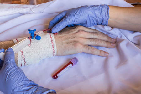 Doctor blood drawn with a syringe holding the arm of a man in hospitalの写真素材