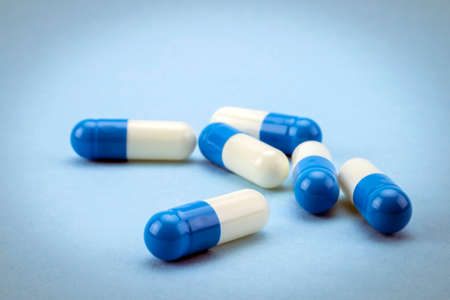 Many medicines blue and white capsules on blue background