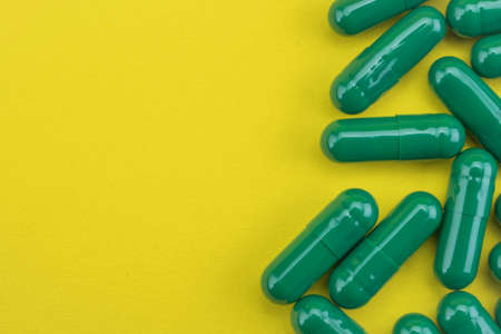 Green pills capsules medicine on yellow background