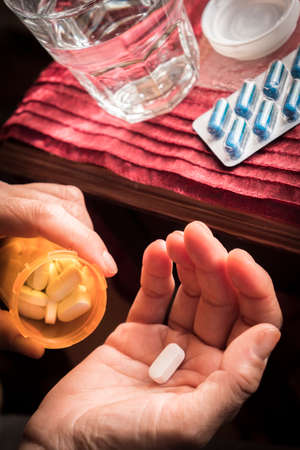 Women take white capsule with left hand from a ambar bottle