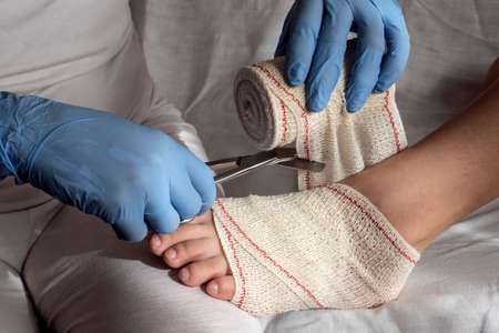 Close-up Of A Nurse Tying Bandage On Patient's Footの写真素材