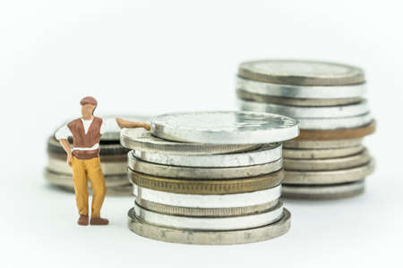 Miniature man next to a few coins, concept economy