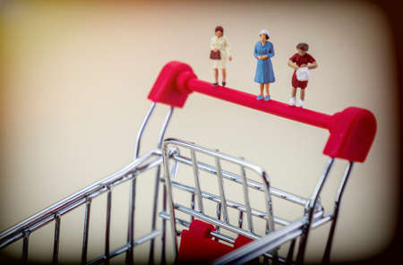 Miniature figures of women on a shopping cart, concept of economyの写真素材