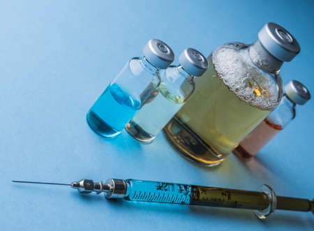 Several vials and syringe in laboratory, conceptual image