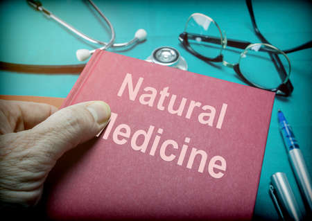 Doctor supports a book of natural medicine in a medical laboratoryの写真素材