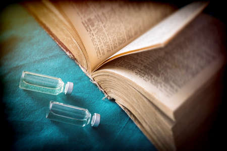 Vials with medication next to an old book of medicine, conceptual imageの写真素材