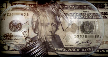 A lightbulb on dollar bill, energy saving conceptの写真素材