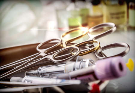 Scissors and vials of blood samples in a tray on a table of a hospital, conceptual image