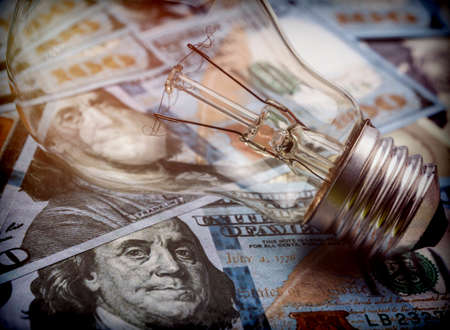 A lightbulb on dollar bill, energy saving conceptの写真素材