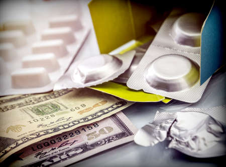 Some medicines next to a block of tickets of dollar, conceptual imageの写真素材