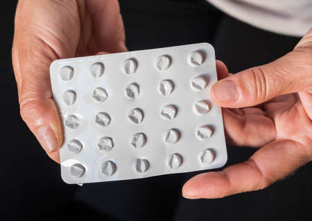 Woman holds blister pack of pills empty in their hands, conceptual image
