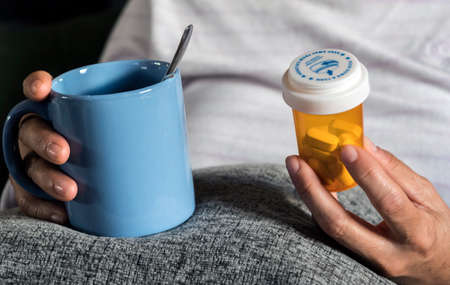 Woman examining medication treatment, several boats in the hand, conceptual imageの写真素材