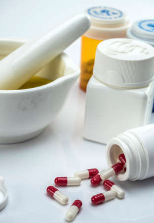 Mortar pharmaceutical next to several cans of capsules isolated on white backgroundの写真素材