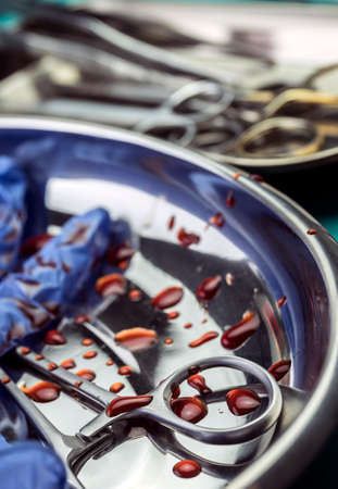 Gloves blue and scissors stained with blood on a tray in an operating theater, conceptual imageの写真素材