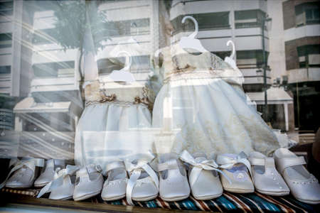 Dresses and shoes to make first communion reflected in showcase, conceptual imageの写真素材