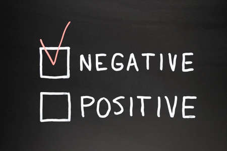 Negative and positive written on a black slate with chalk. In red marked negative box, conceptual imageの写真素材