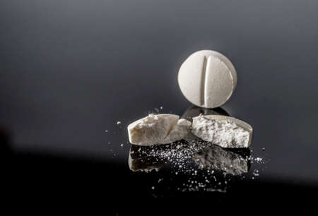 White pill by half isolated in black background, conceptual imageの写真素材