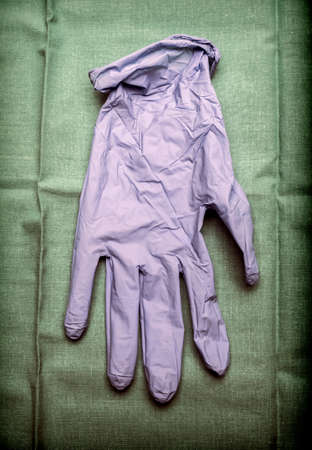 Glove of latex blue on green cloth in an operating theater, conceptual imageの写真素材