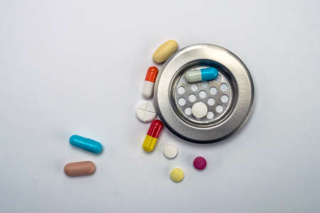 Tablets in a drain isolated on white background, conceptual imageの写真素材