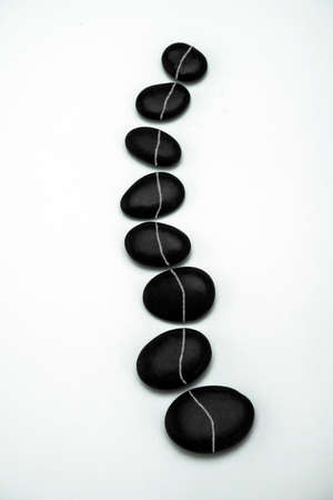 Formation of black stones imitating the vertebral column, isolated in white background, conceptual imageの写真素材