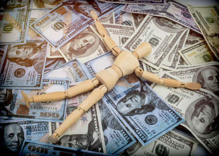 Doll made of wood lying on a lot of banknotes of dollar Americans, conceptual imageの写真素材
