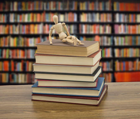 Wooden doll on some books in a library, conceptual imageの写真素材