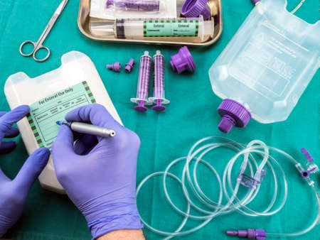 Nurse writing data of sick on sticker on team of enteral nutrition, palliative care in hospital, conceptual image, composition hotizontalの写真素材