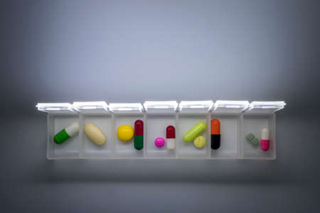 weekly pillbox with medication, conceptual image, horizontal composition