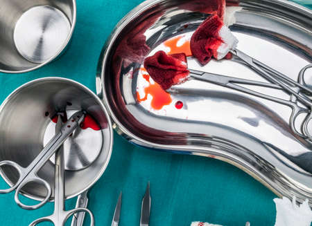 Scissors surgical with torundas soaked with blood on a tray metal in an operating theater,...