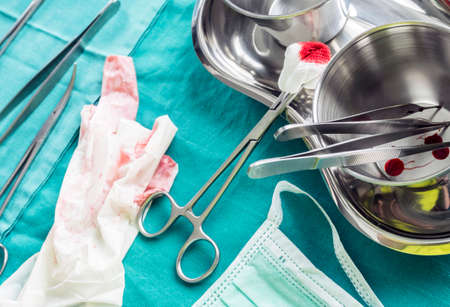 Scissors surgical with torunda soaked with blood on a tray metal in an operating theater,...