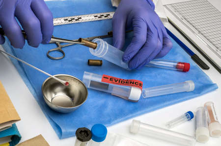 Scientific police picking up bullet cap with tweezers, conceptual image, horizontal composition