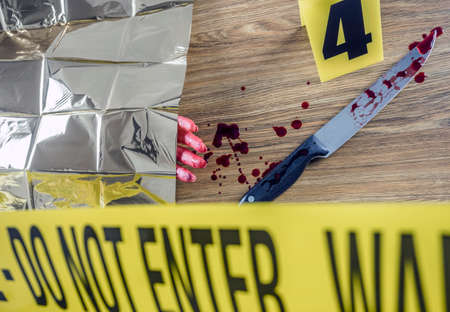 Murder scene for cutting weapon, gory hand along with a knife with blood, conceptual image