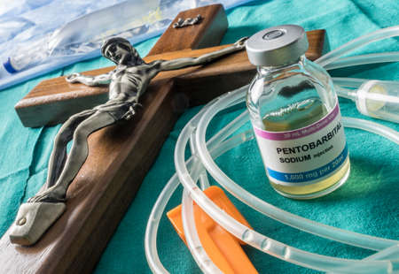 Vial with doses of pentobarbital next to a crucifix, Debate between life and death, religious belief in the face of euthanasia, conceptual imageの写真素材