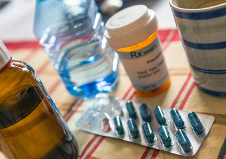 Medication during breakfast, capsules next to a glass of water, conceptual imageの写真素材