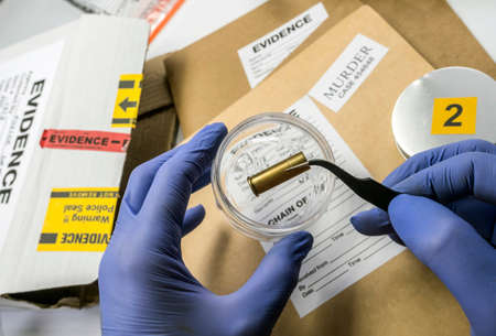 Scientific police examining a bullet cap in ballistic Laboratory, conceptual image