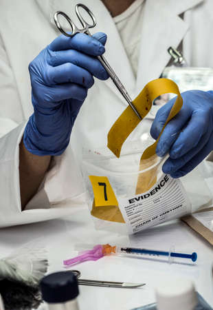 Specialized police analyzes gum with traces of blood from a victim overdose with tweezers, conceptual imageの写真素材
